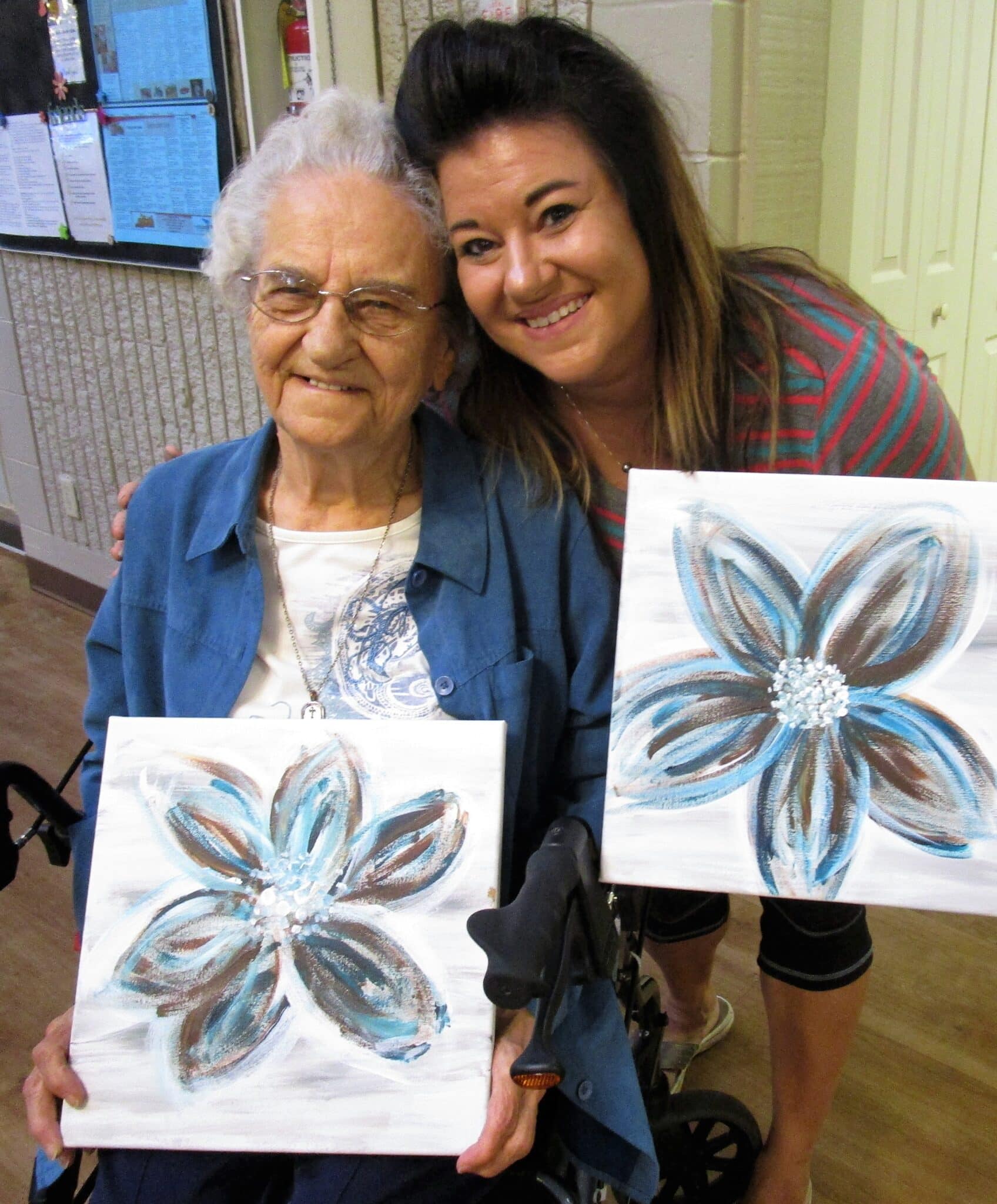 A photo of a senior woman and a younger woman displaying their artwork at Kensington Evergreen.